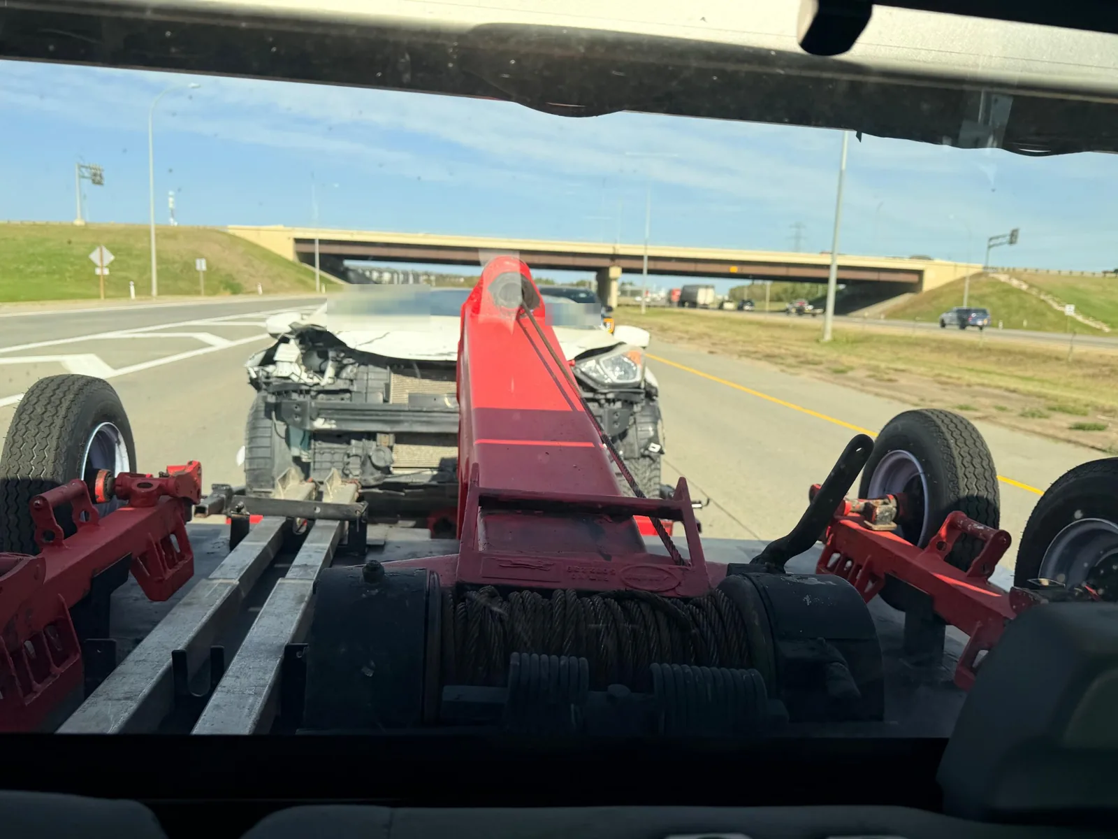 Ironline tow truck towing a collision-damaged Hyundai Elantra on Anthony Henday Drive in Edmonton