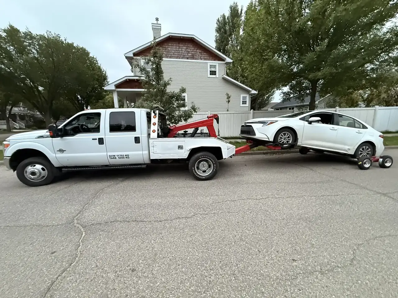 Ironline tow truck towing a white Toyota Corolla on dollies in Edmonton