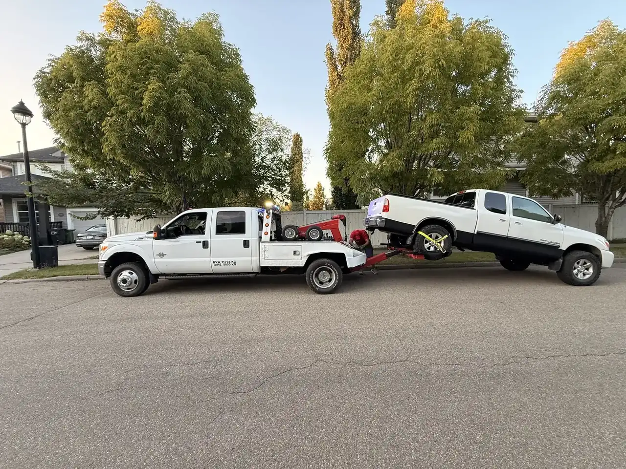 Ironline tow truck towing a white Toyota Tundra pickup on an Edmonton residential street