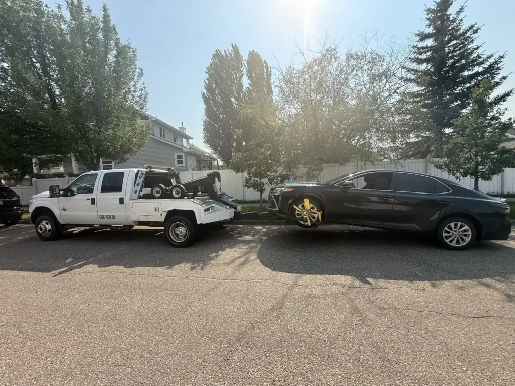 Ironline tow truck towing a dark sedan from a residential street in Edmonton
