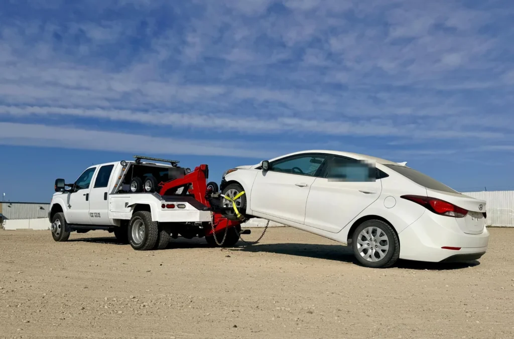 Ironline tow truck lifting a white sedan with a wheel lift in Edmonton